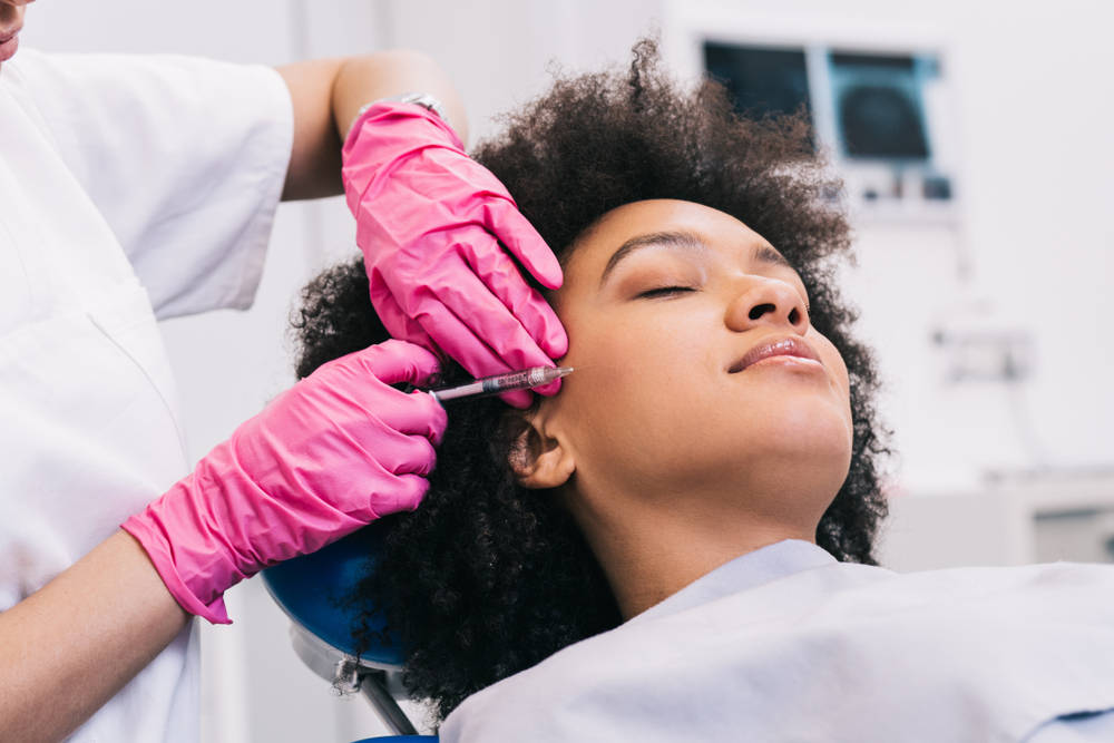 Young woman receiving a hyaluronic acid filler injection at a medical aesthetics clinic