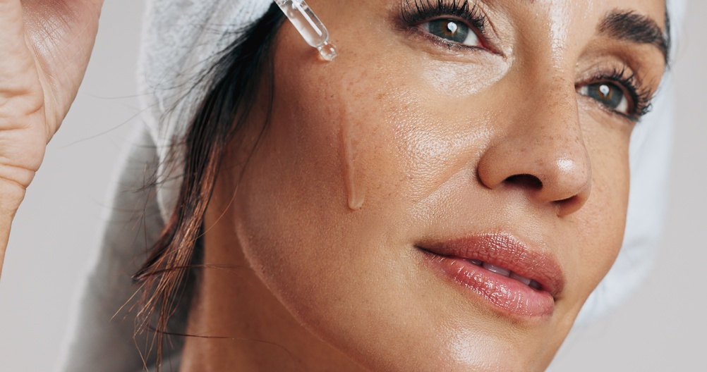 Woman applying hyaluronic acid serum to her face during a skincare treatment